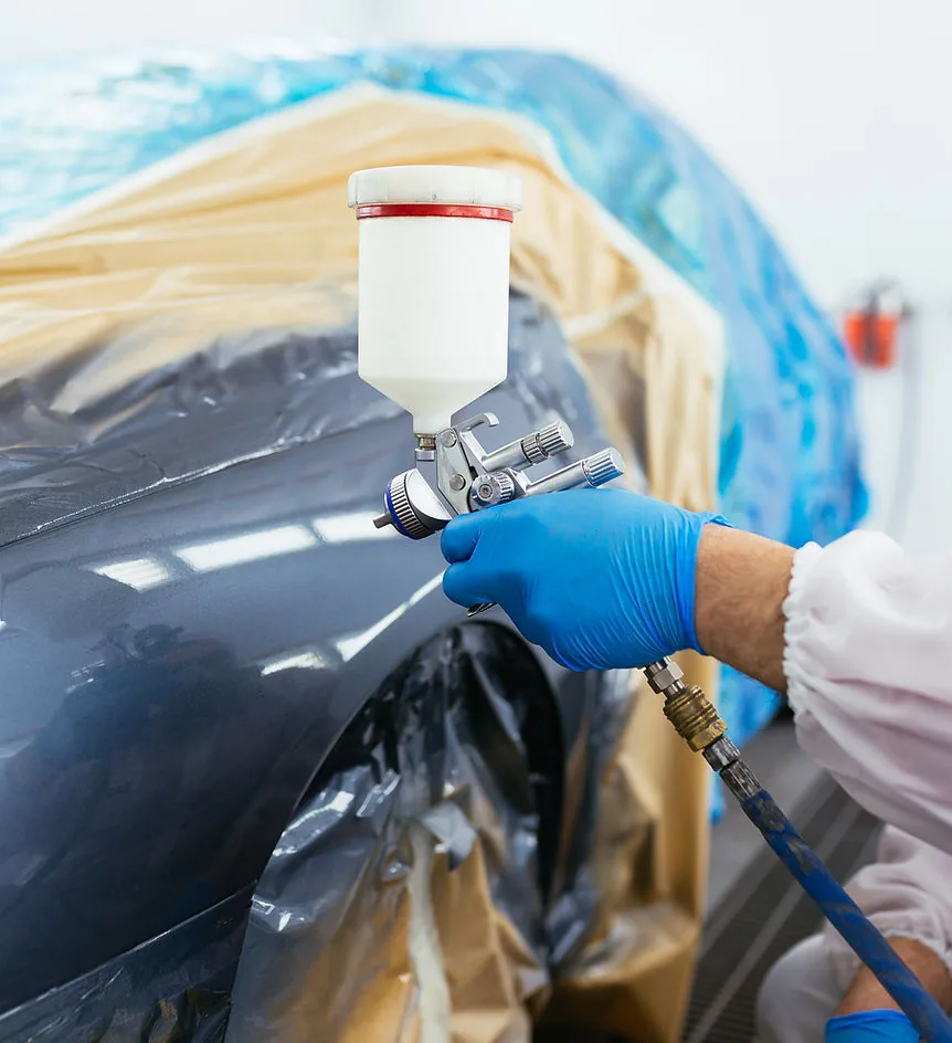 Car paintwork repair specialist applying matched paint to a panel in Barnstaple